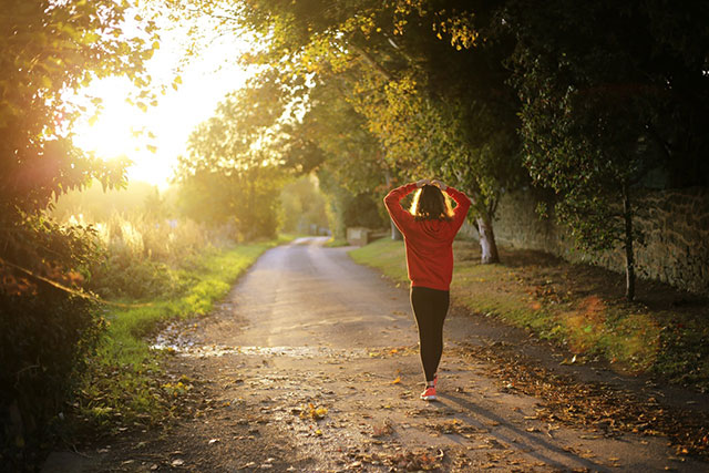 woman walking on path in early morning sun